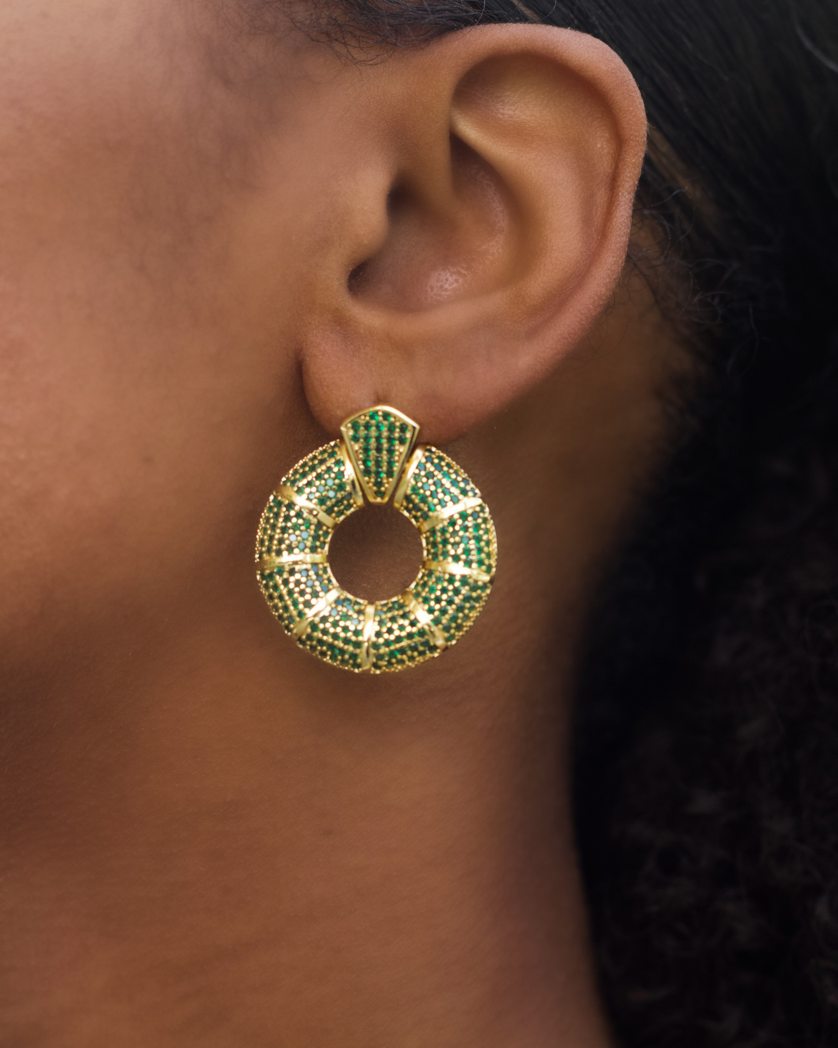 Model wearing green donut hoop earrings