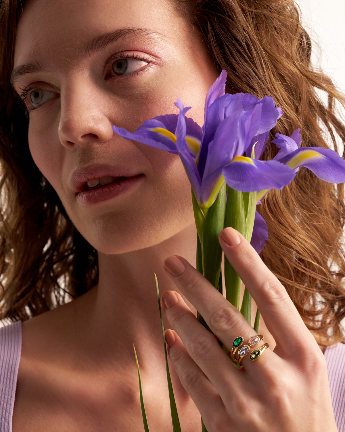 Woman wearing gold gemstone ring with purple iris flowers