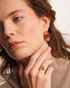 Close-up of woman wearing gold gemstone earrings