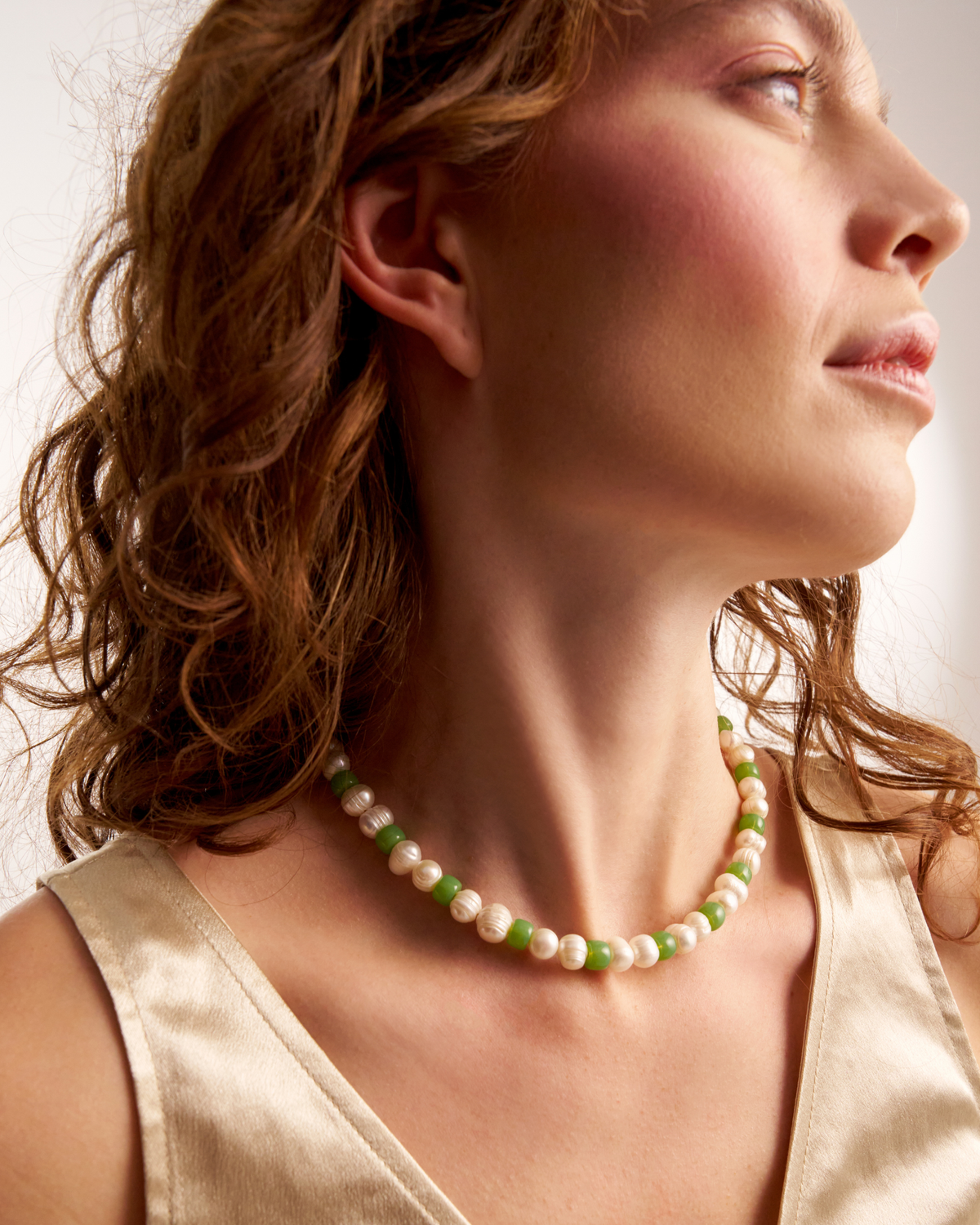 Woman styling delicate green pearl necklace