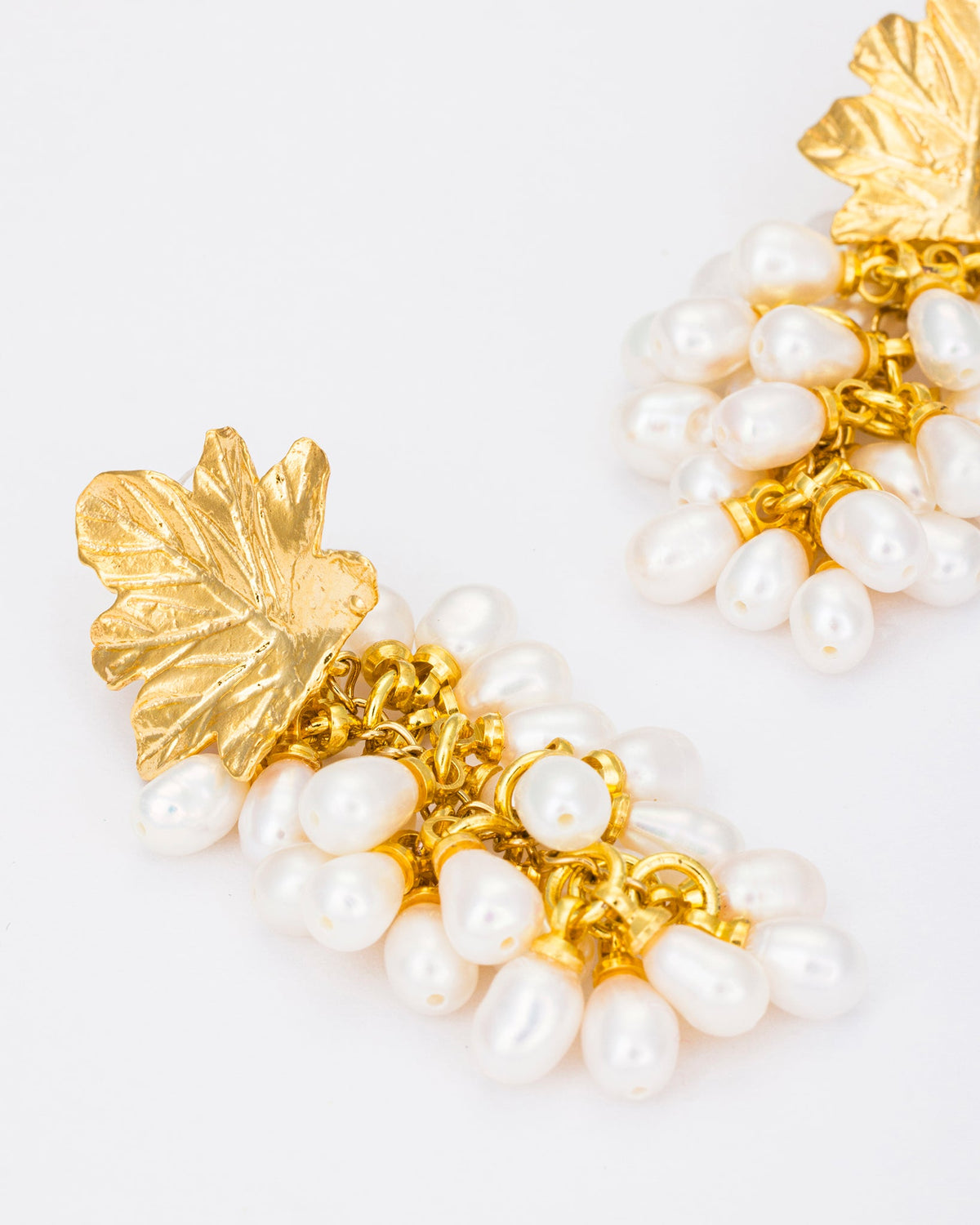 Close-up detail of pearl cluster earrings showcasing gold leaf texture and pearl arrangement