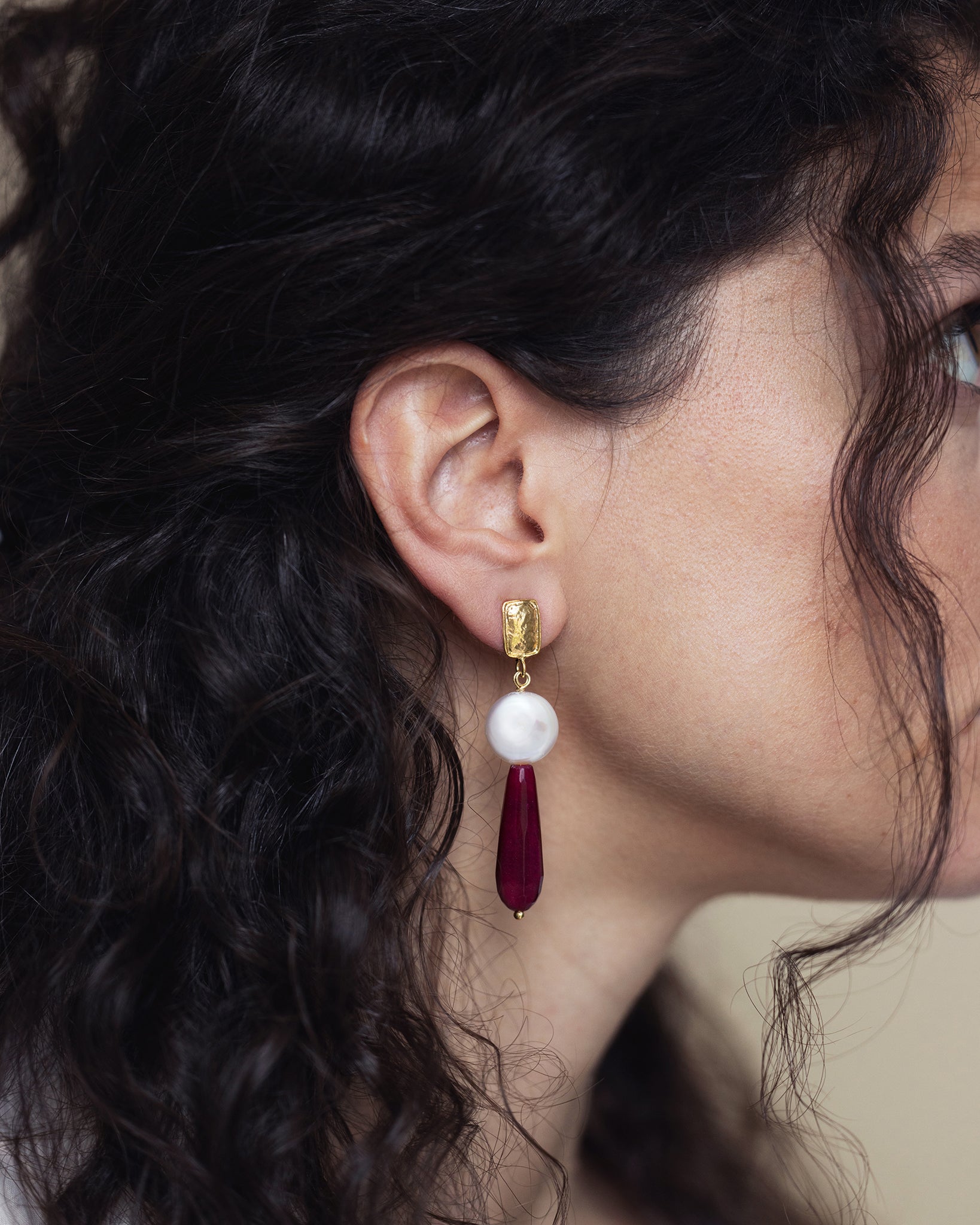 Woman wearing ruby and baroque pearl drop earrings in an elegant evening style