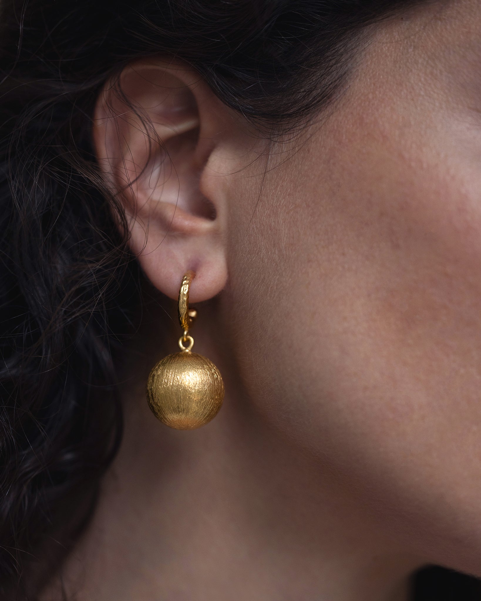 Woman wearing textured gold sphere earrings