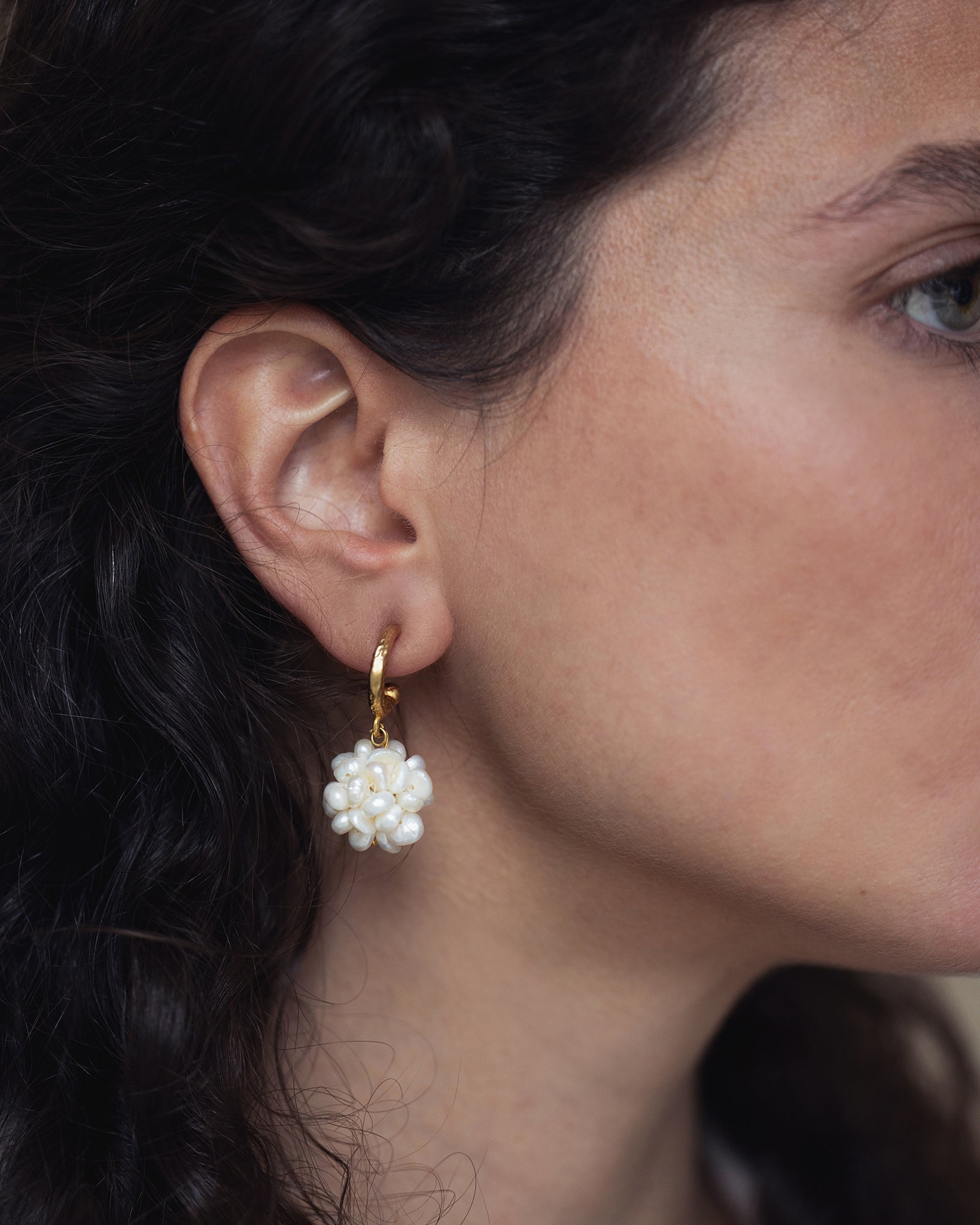 Woman wearing pearl bouquet hoop earrings with delicate freshwater pearl clusters