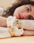 Woman wearing gold bangle bracelet with green zircon details