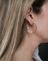 Woman wearing freshwater pearl inside-out gold hoop earrings in a minimal everyday look