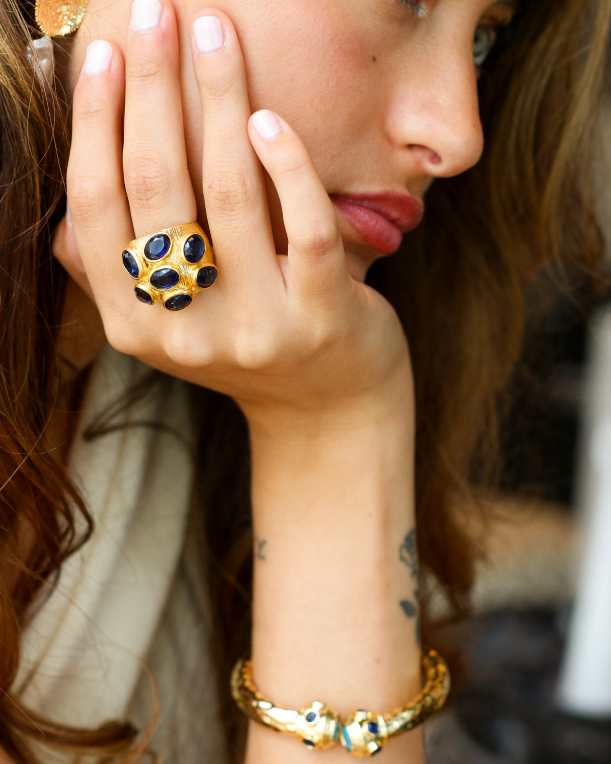 Model wearing gold sapphire multi-gemstone cocktail ring