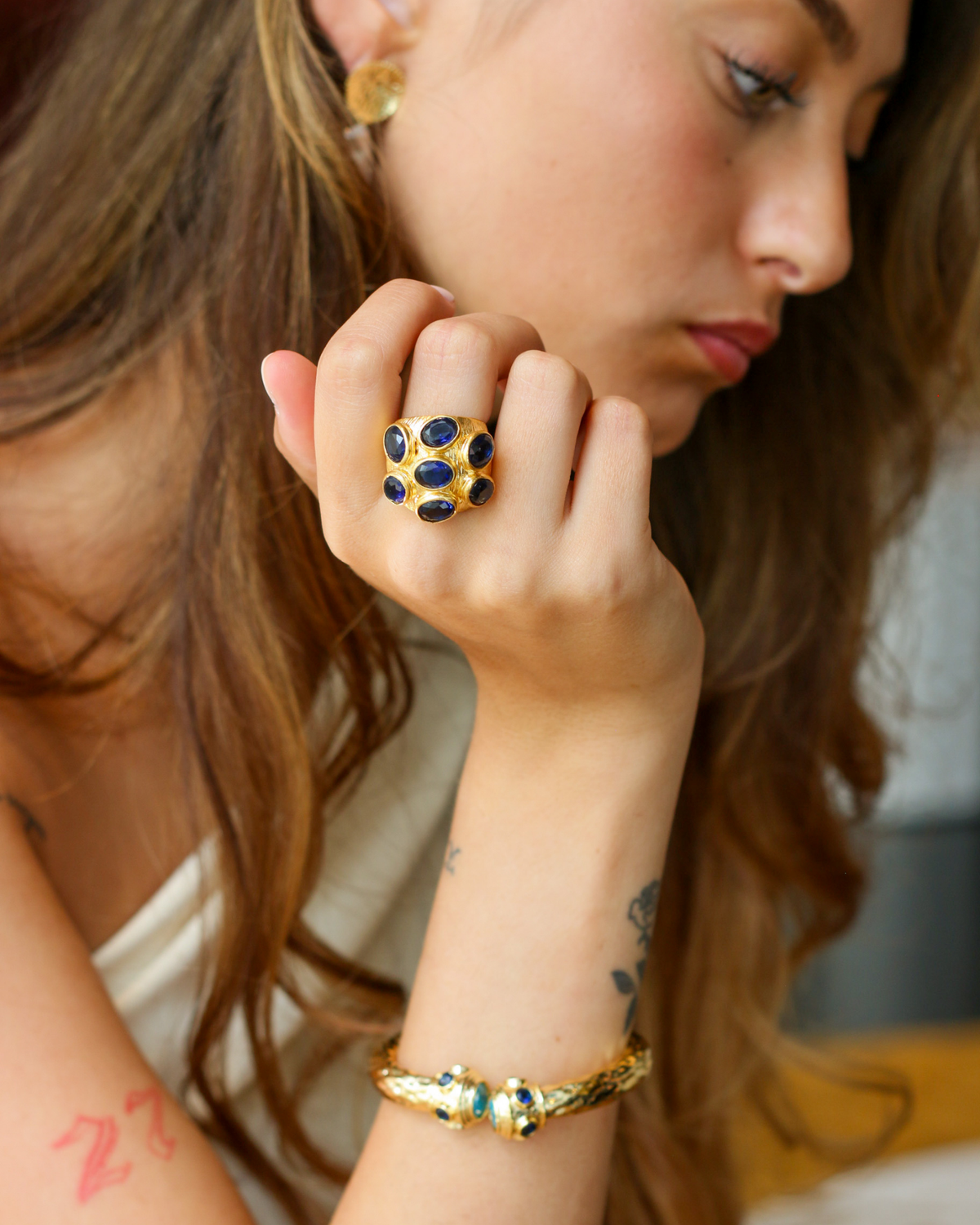 Gold sapphire statement ring styled with layered jewelry