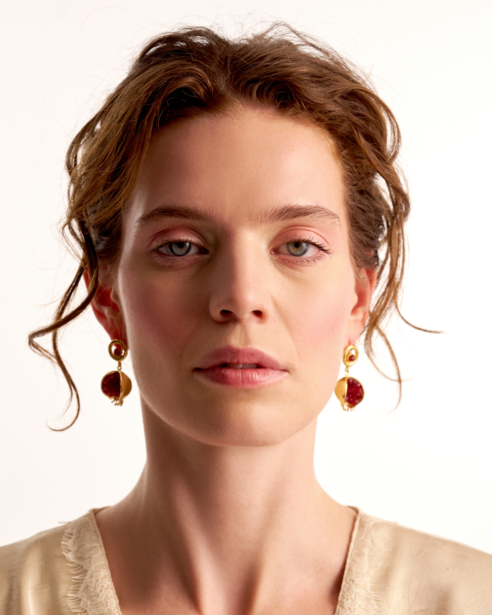 Woman wearing red jade pomegranate earrings with elegant styling