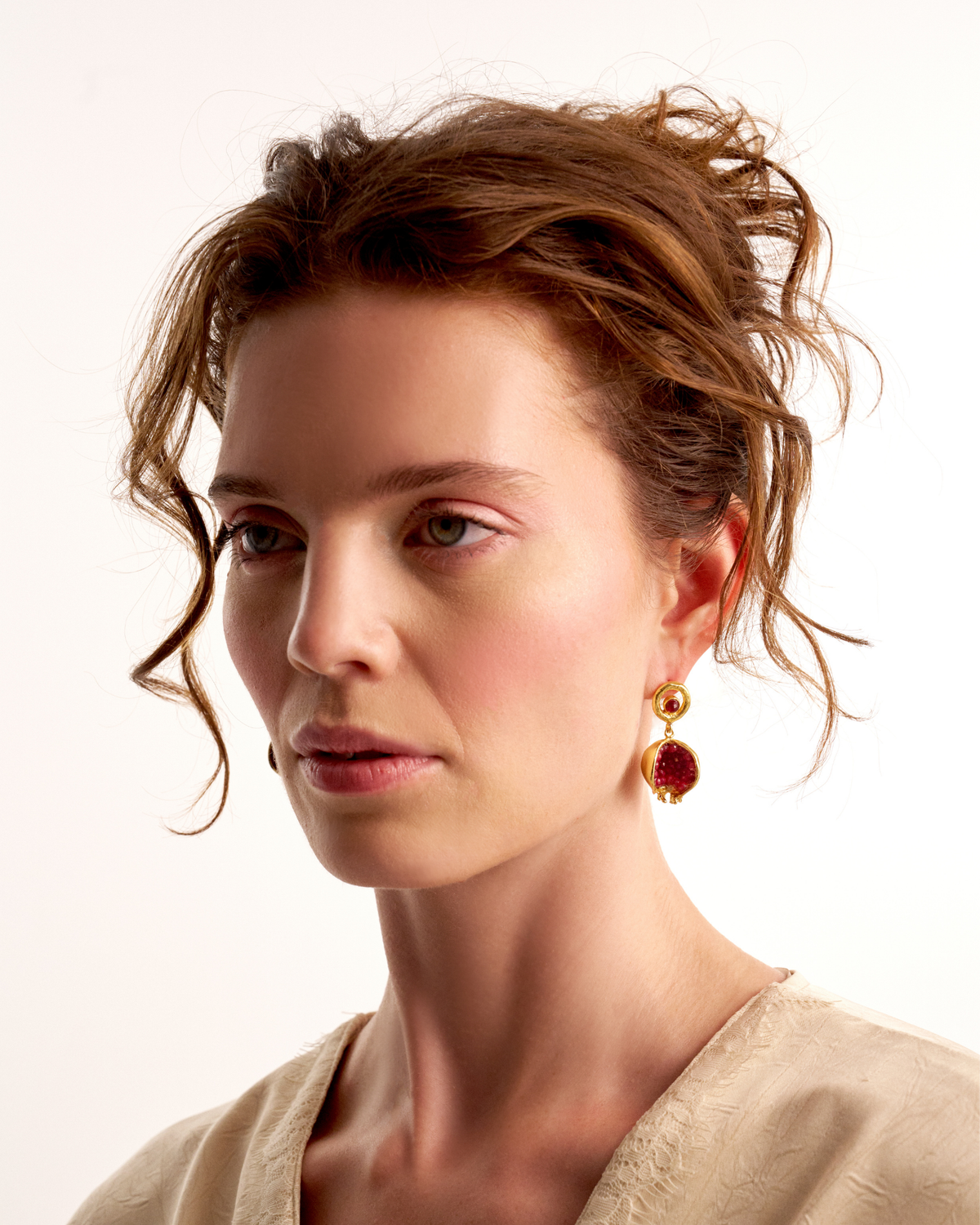 Side profile of woman wearing pomegranate-inspired red gemstone earrings
