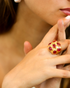Close-up of gold blush cocktail ring with layered jewelry