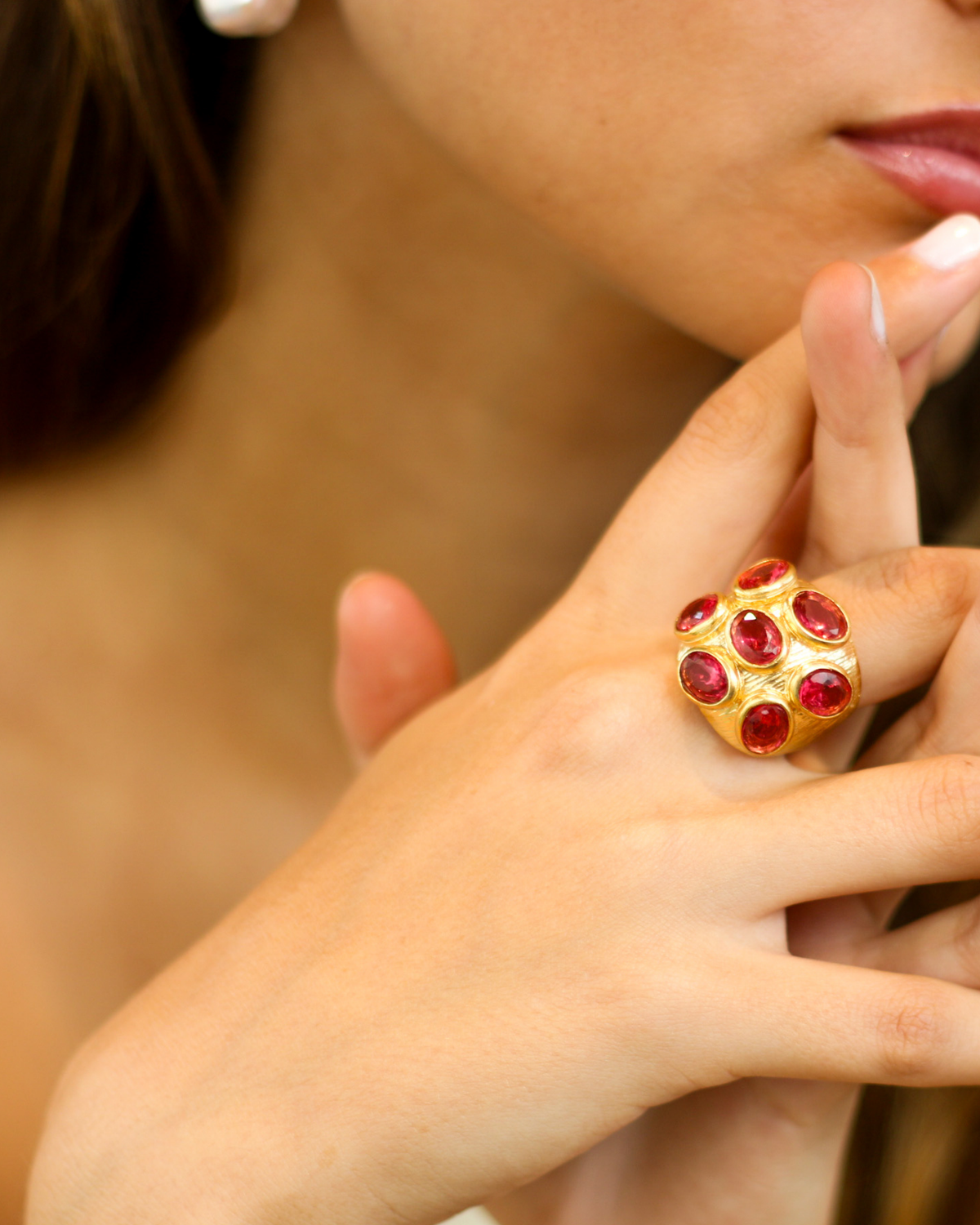 Close-up of gold blush cocktail ring with layered jewelry