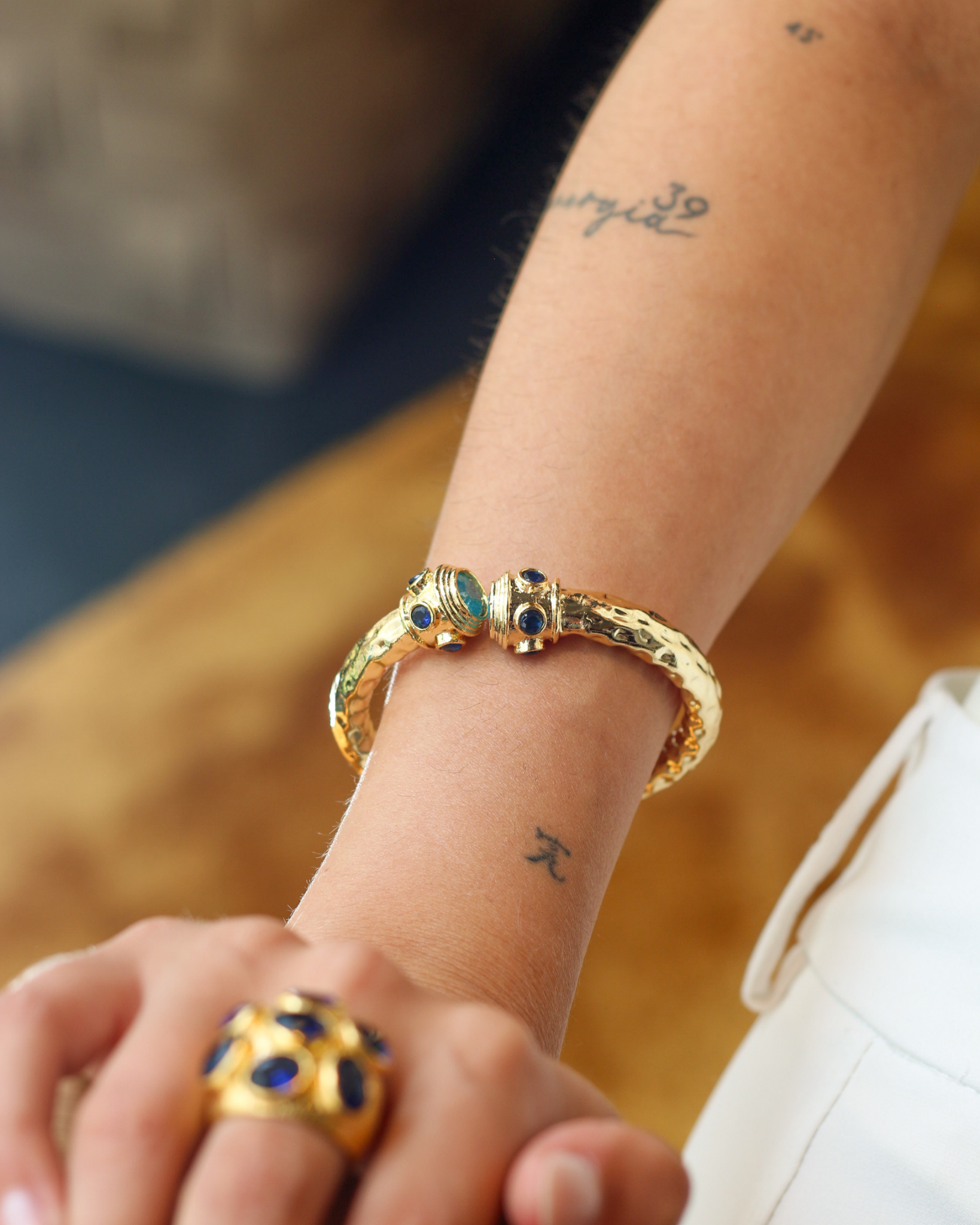Woman wearing gold zircon bangle bracelet with statement jewelry