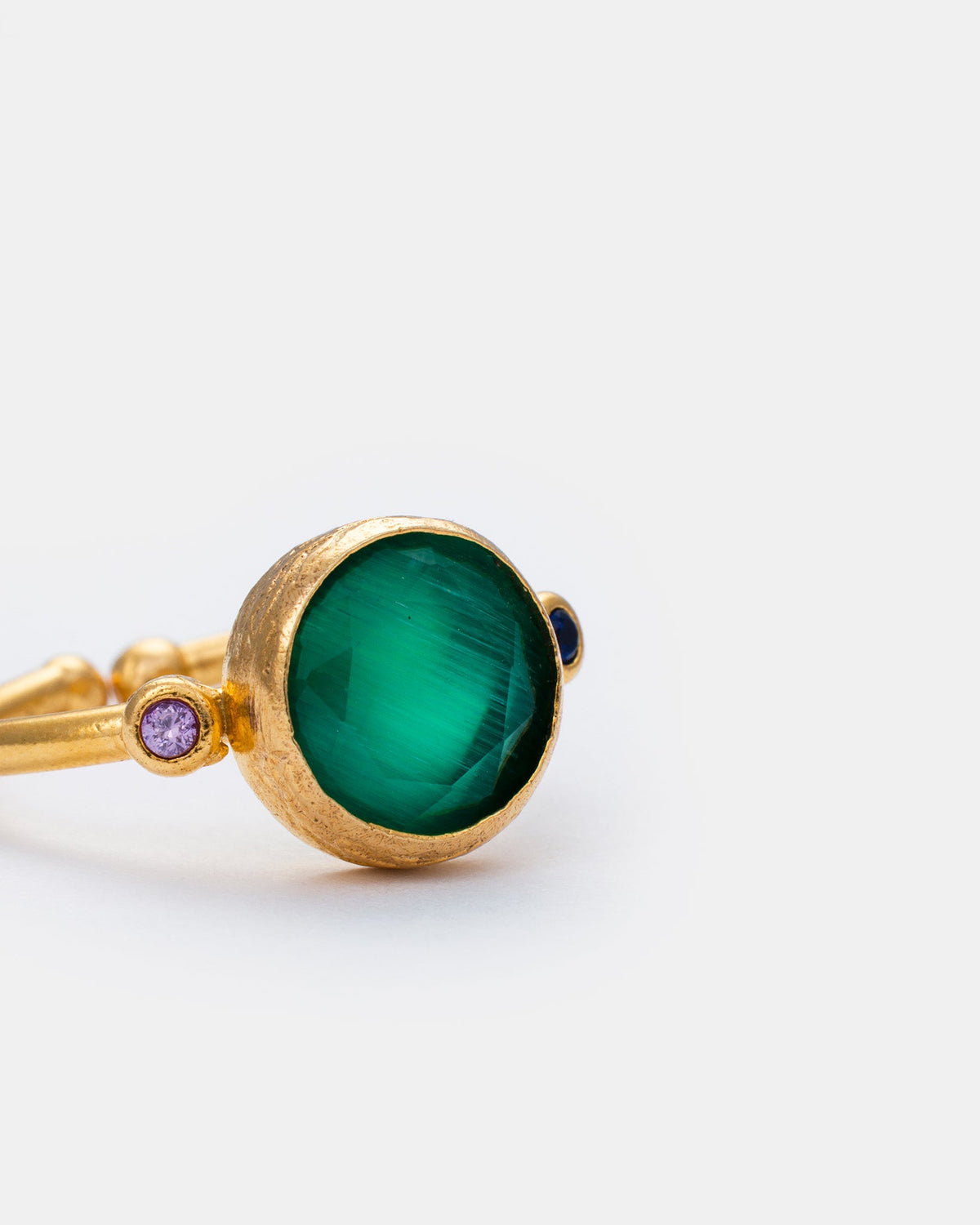 Close-up detail of green cat eye gemstone ring with gold-plated brass setting
