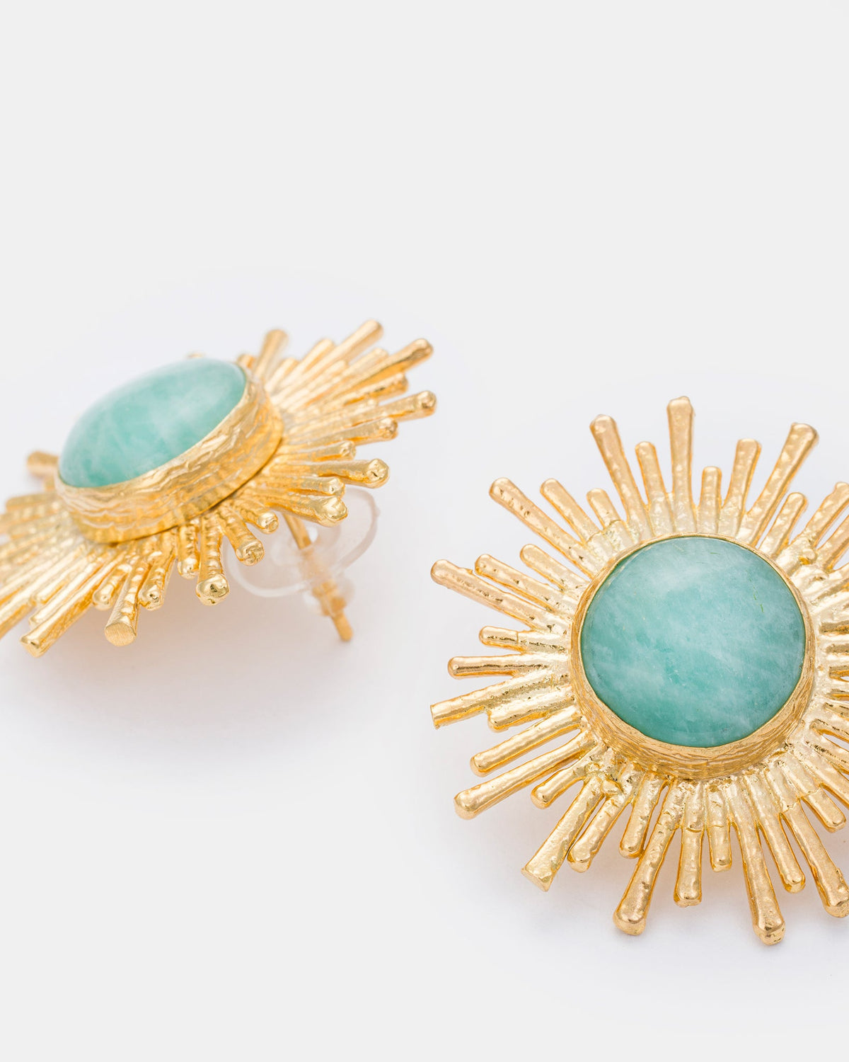 Close-up detail of gold sunburst earrings highlighting green aventurine gemstones