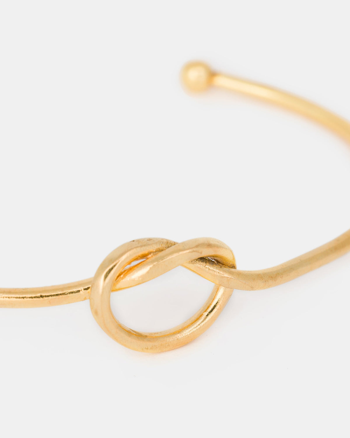 Close-up of gold-plated knot detail on open bangle bracelet
