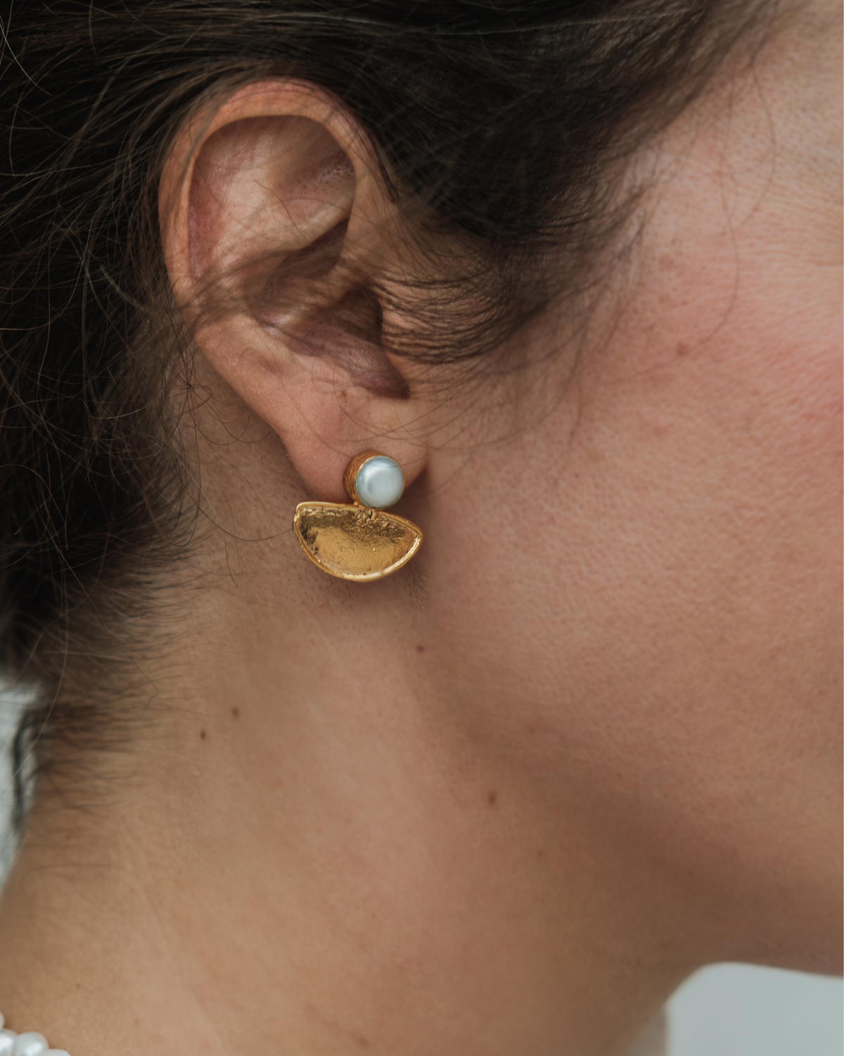 Woman wearing pearl and gold crescent earrings