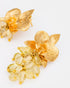 Close-up detail of citrine orchid earrings featuring textured gold petals and gemstone clusters