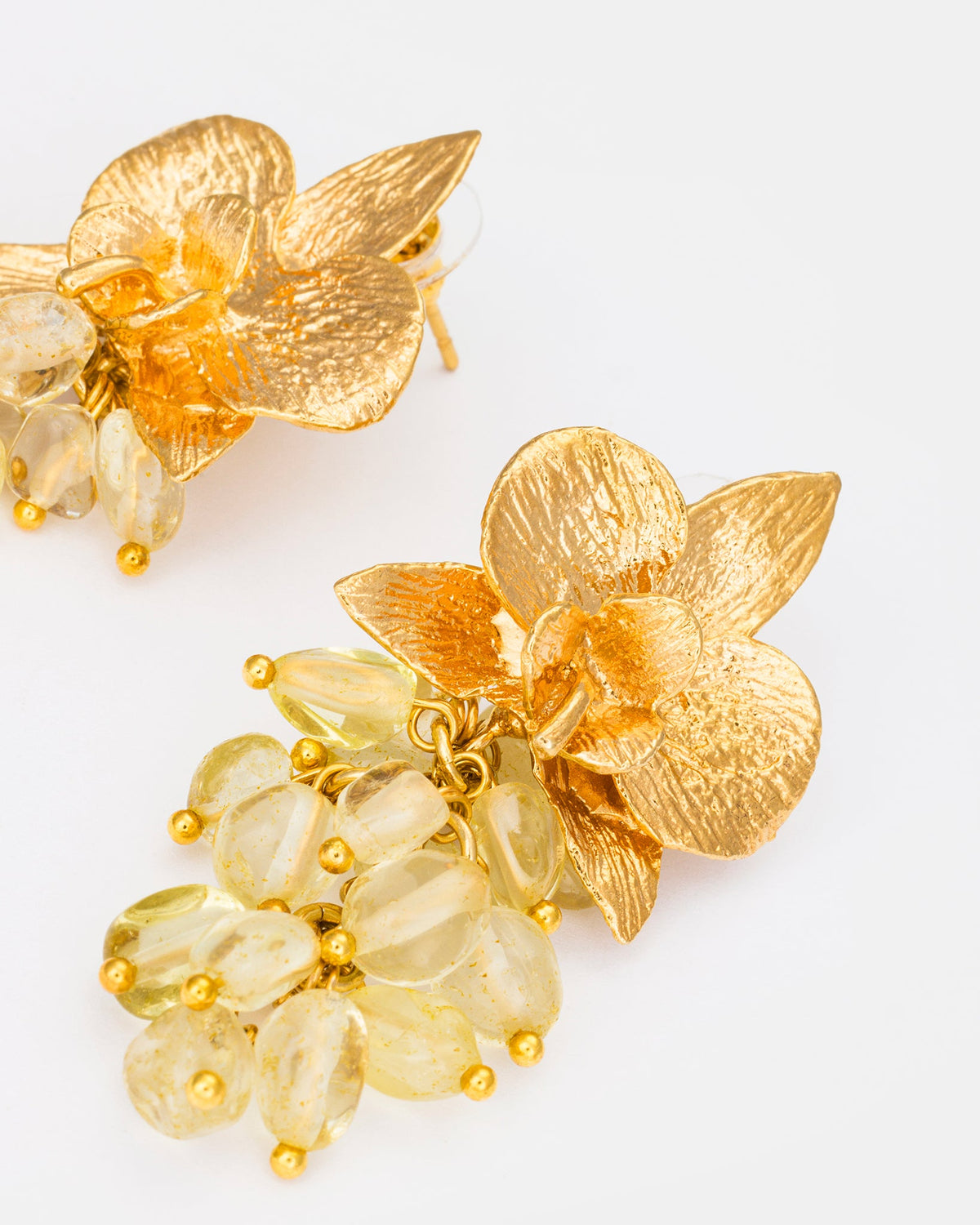 Close-up detail of citrine orchid earrings featuring textured gold petals and gemstone clusters