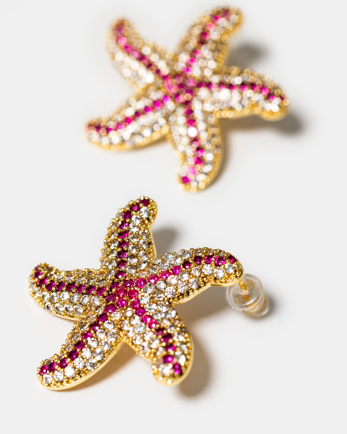 Close-up of pink starfish earrings in gold-tone finish